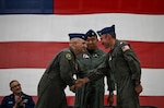 Capt. Neal Corbin (left) and Cmdr. Michael Flint (right) shake hands after a change-of-command ceremony that Rear Adm. Arex Avanni (center) presided over at Coast Guard Air Station Astoria in Warrenton, Ore., July 16, 2026. Corbin has served as Coast Guard Air Station Astoria’s commanding officer since 2024. (U.S. Coast Guard photo by Petty Officer 3rd Class William Kirk)