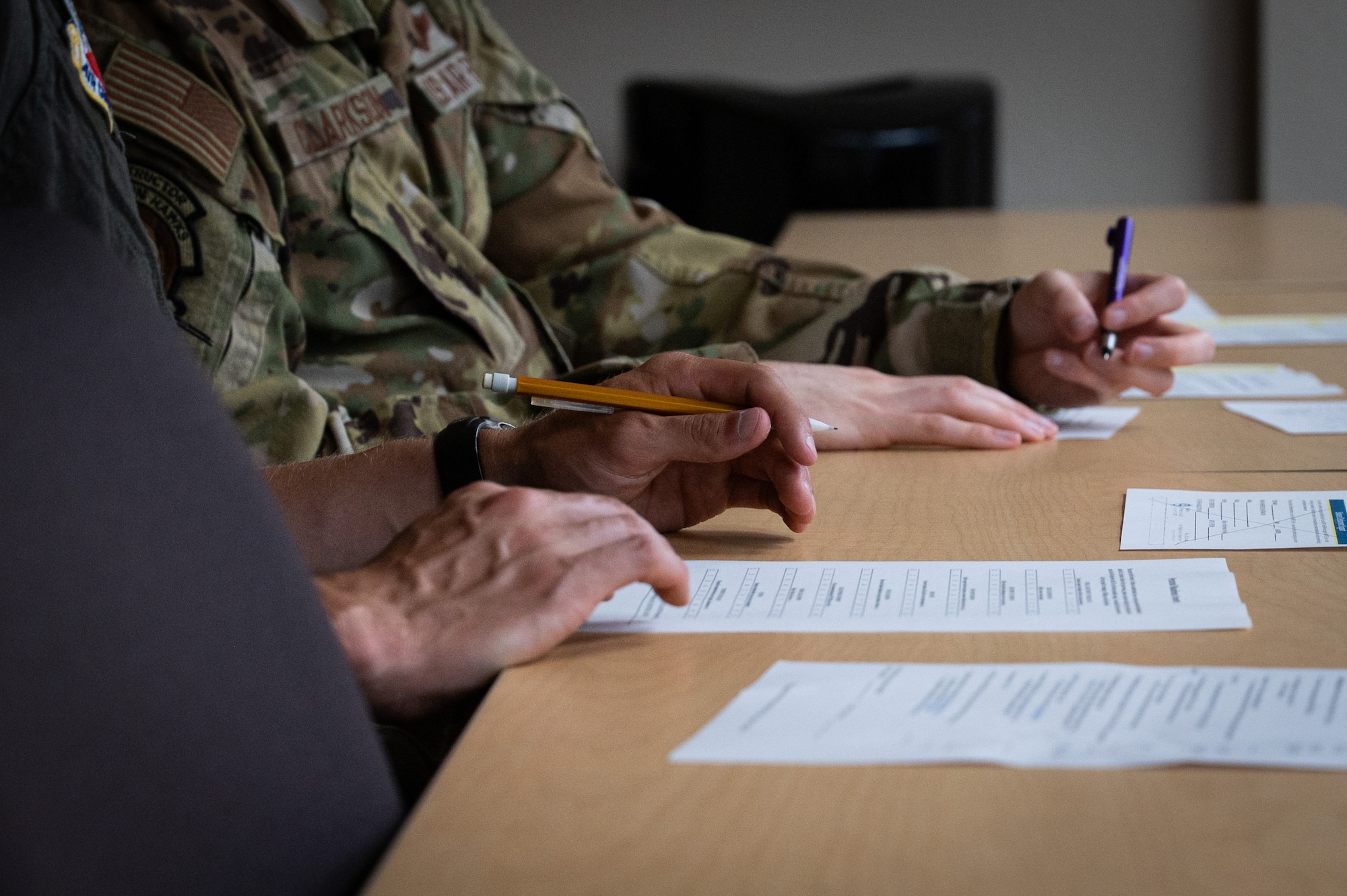 A photo of people's hands signing paperwork against a desk.