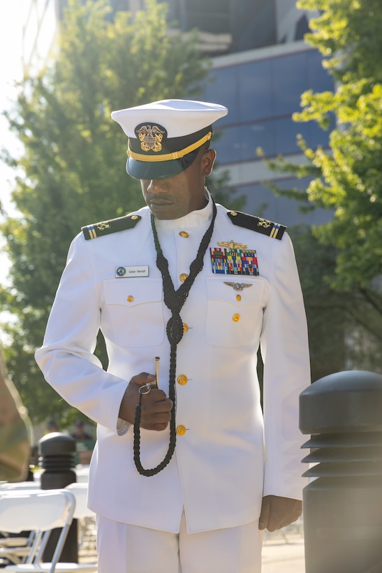 A man in a white Navy uniform stands at the ready.