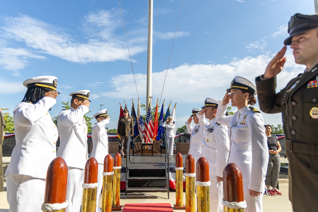 A military ceremony outside with a red carpet with full size bullets leading up to the stage.