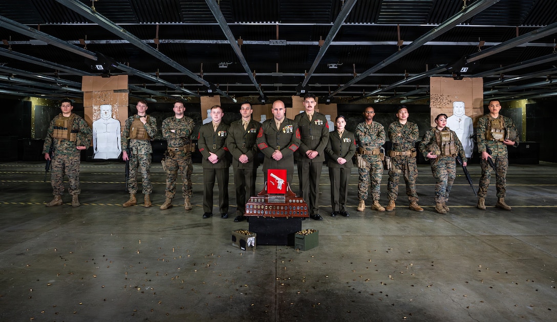 U.S. Marines assigned to Headquarters and Headquarters Squadron (HHS), Marine Corps Air Station Iwakuni, pose for a group photo with the Shively trophy in the Indoor Small Arms Range at MCAS Iwakuni, Japan, Feb. 20, 2026.  The Iwakuni shooting team won the 2025 Fare East Marine Corps Marksmanship Competition pistol trophy. (U.S. Marine Corps photo by GySgt. Miguel A. Rosales)