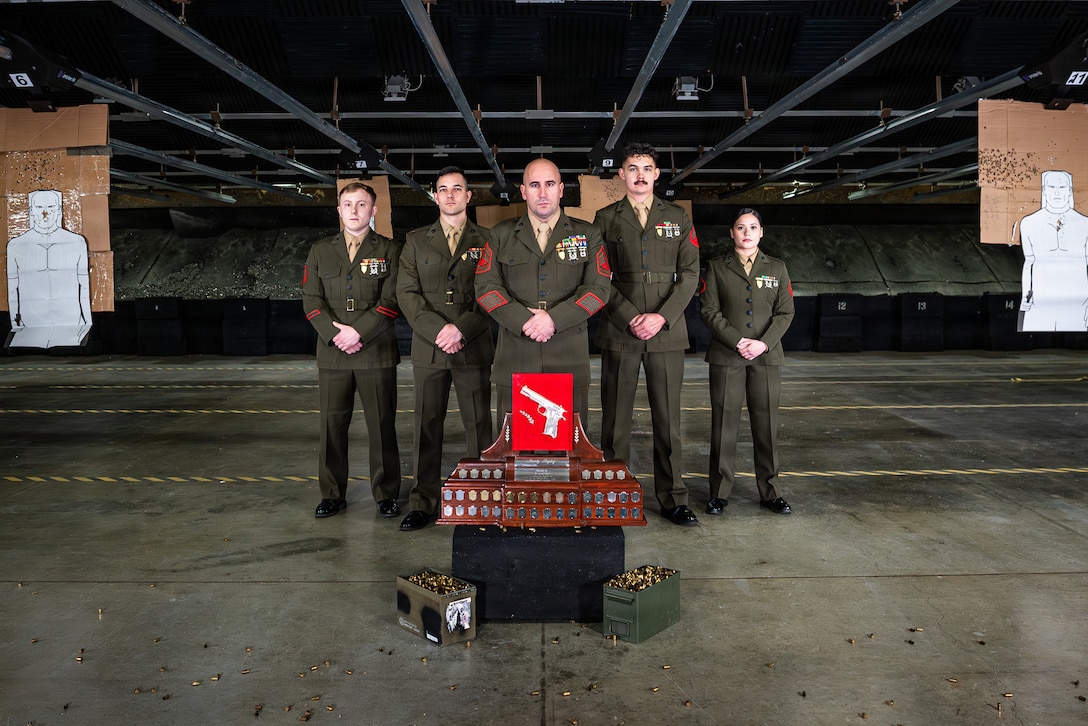 U.S. Marines assigned to Headquarters and Headquarters Squadron (HHS), Marine Corps Air Station Iwakuni, pose for a group photo with the Shively trophy in the Indoor Small Arms Range at MCAS Iwakuni, Japan, Feb. 20, 2026.  The Iwakuni shooting team won the 2025 Fare East Marine Corps Marksmanship Competition pistol trophy. (U.S. Marine Corps photo by GySgt. Miguel A. Rosales)
