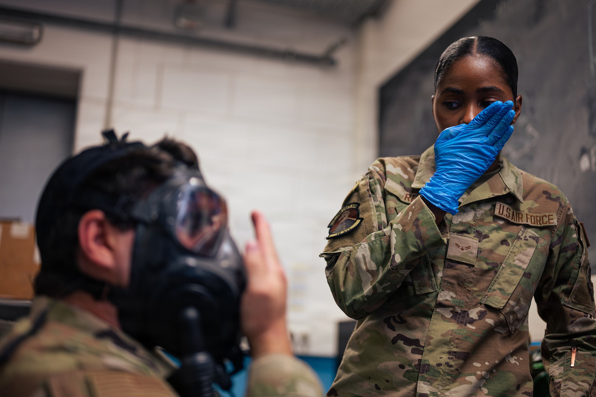 Airman demonstrates for to conducts positive pressure test on gas mask