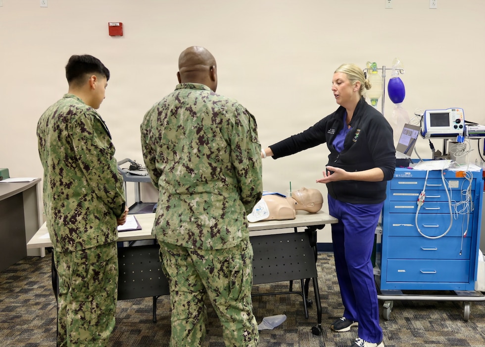 Lt. Cmdr. Nicolle R. Leftwich (right), emergency management department clinical nurse specialist and patient-centered medical homeport department head, assigned to Navy Medicine Readiness and Training Command Twentynine Palms, teaches hospital corpsmen how to operate an automated external defibrillator (AED) during the command's Annual Nursing and Corpsmen Skills Fair, April 28, 2026. The hands-on training reinforced critical clinical procedures, emergency response skills and communication to strengthen medical readiness and support the delivery of safe, high-quality patient care. (U.S. Navy photo by Christopher Jones, NH/NMRTC Twentynine Palms public affairs officer).