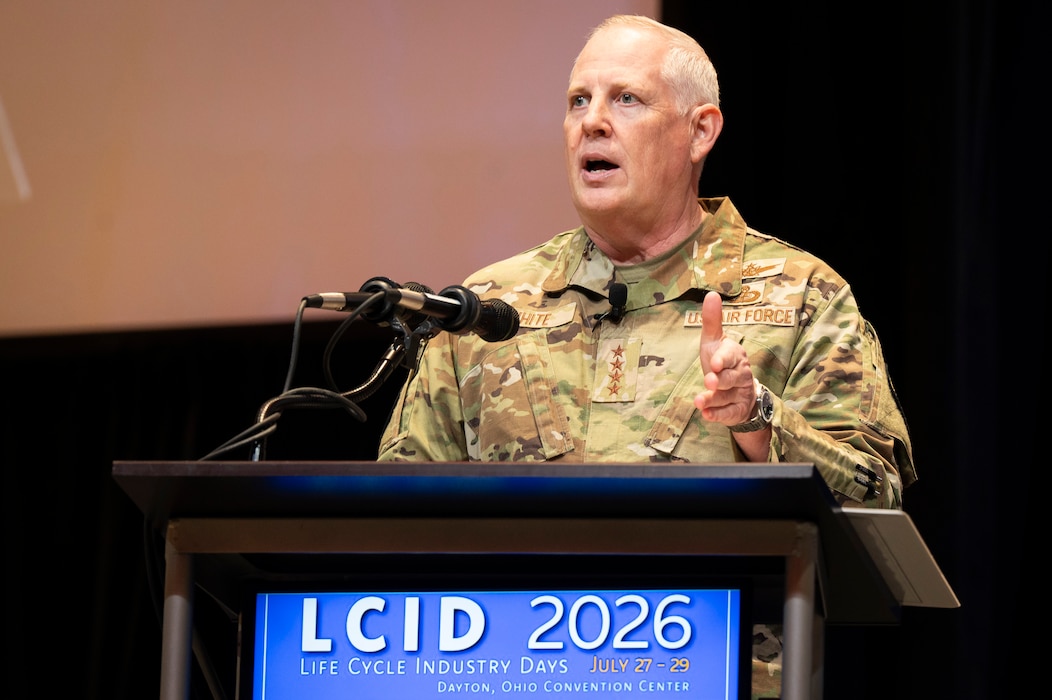 Man in USAF camo stands behind podium and gives speech.