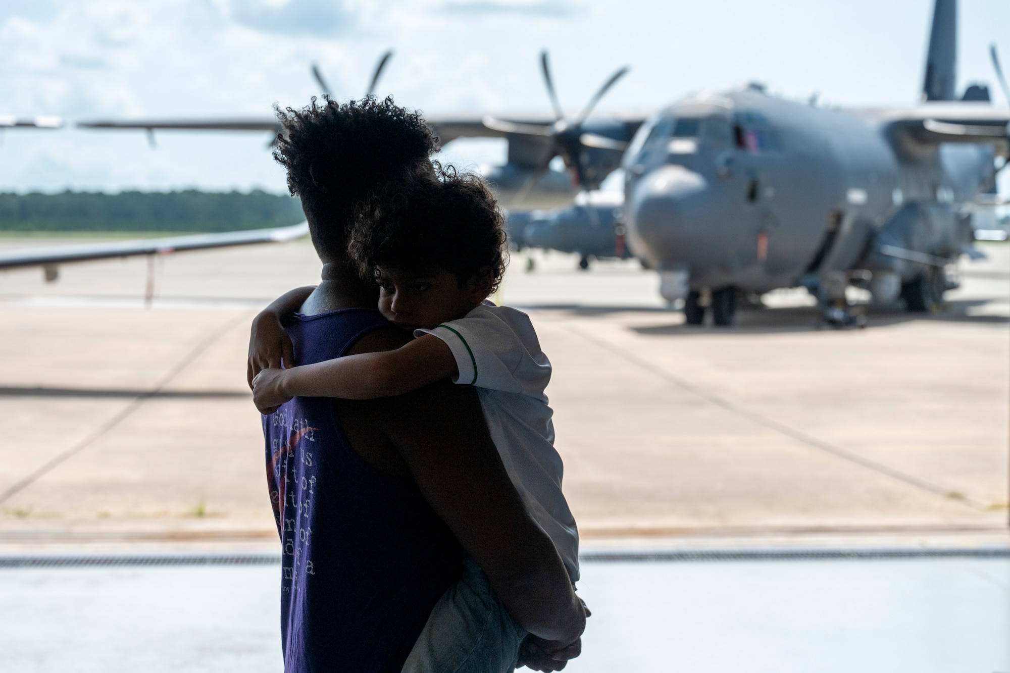 An Airman assigned to the 1st Special Operations Wing holds his child while viewing an AC-130J Ghostrider during an Operation Discovering and Exploring Military Operations homecoming event at Hurlburt Field, Florida, June 27, 2026.