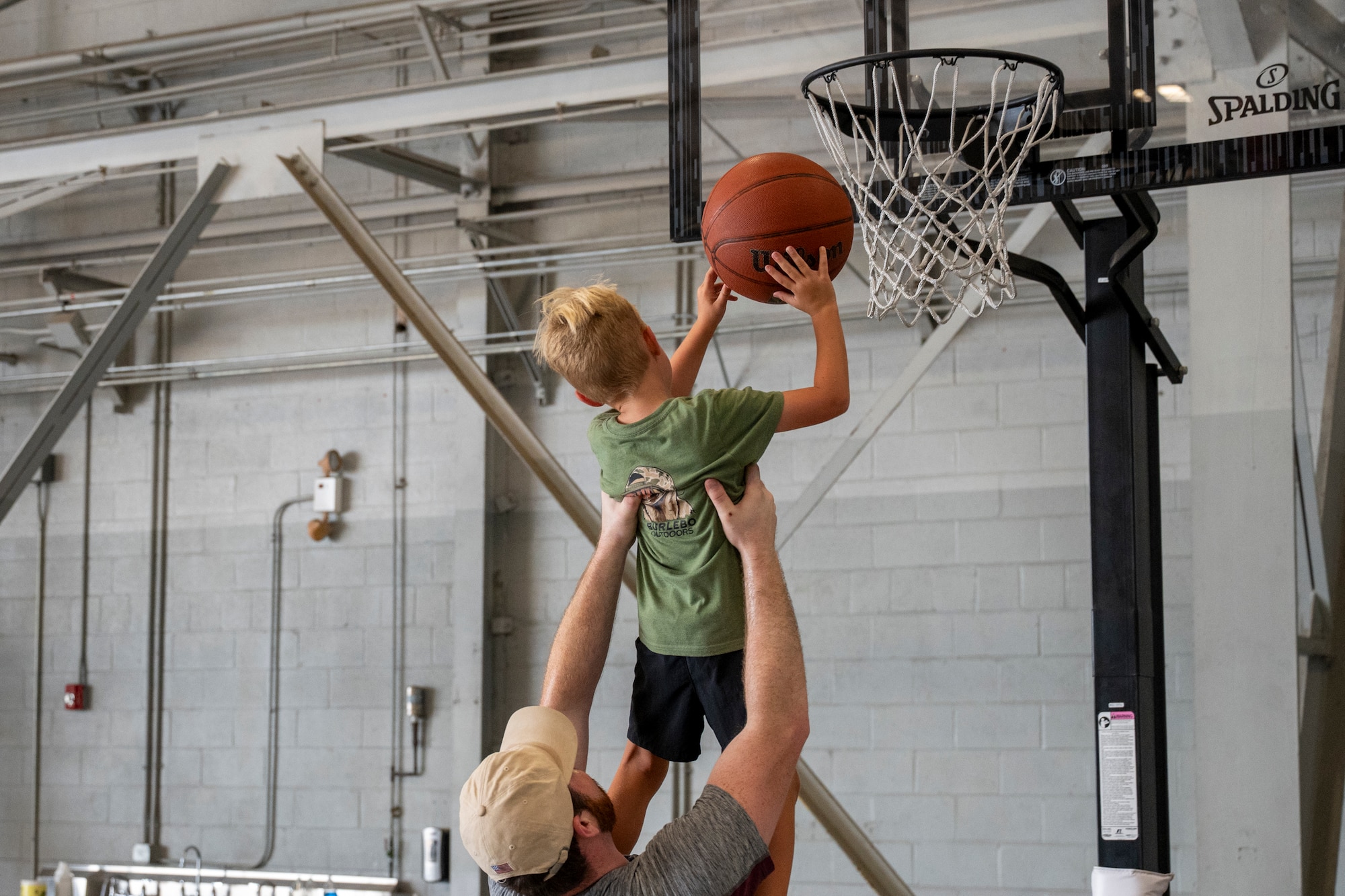 An Airman assigned to the 1st Special Operations Wing helps his child shoot a basketball during an Operation Discovering and Exploring Military Operations homecoming event at Hurlburt Field, Florida, June 27, 2026.