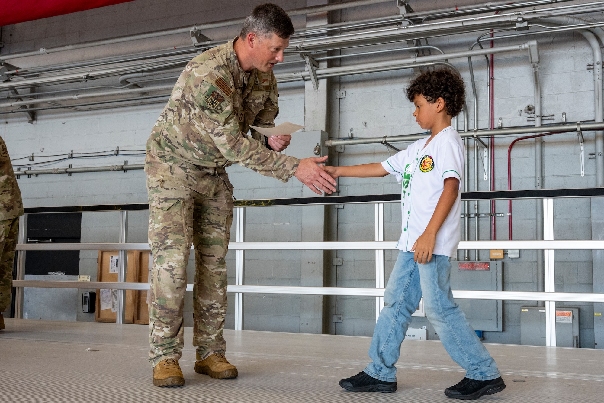 Chief Master Sgt. Joshua Moore, 1st Special Operations Wing command chief, presents a certificate to a child during an Operation Discovering and Exploring Military Operations homecoming event at Hurlburt Field, Florida, June 27, 2026.