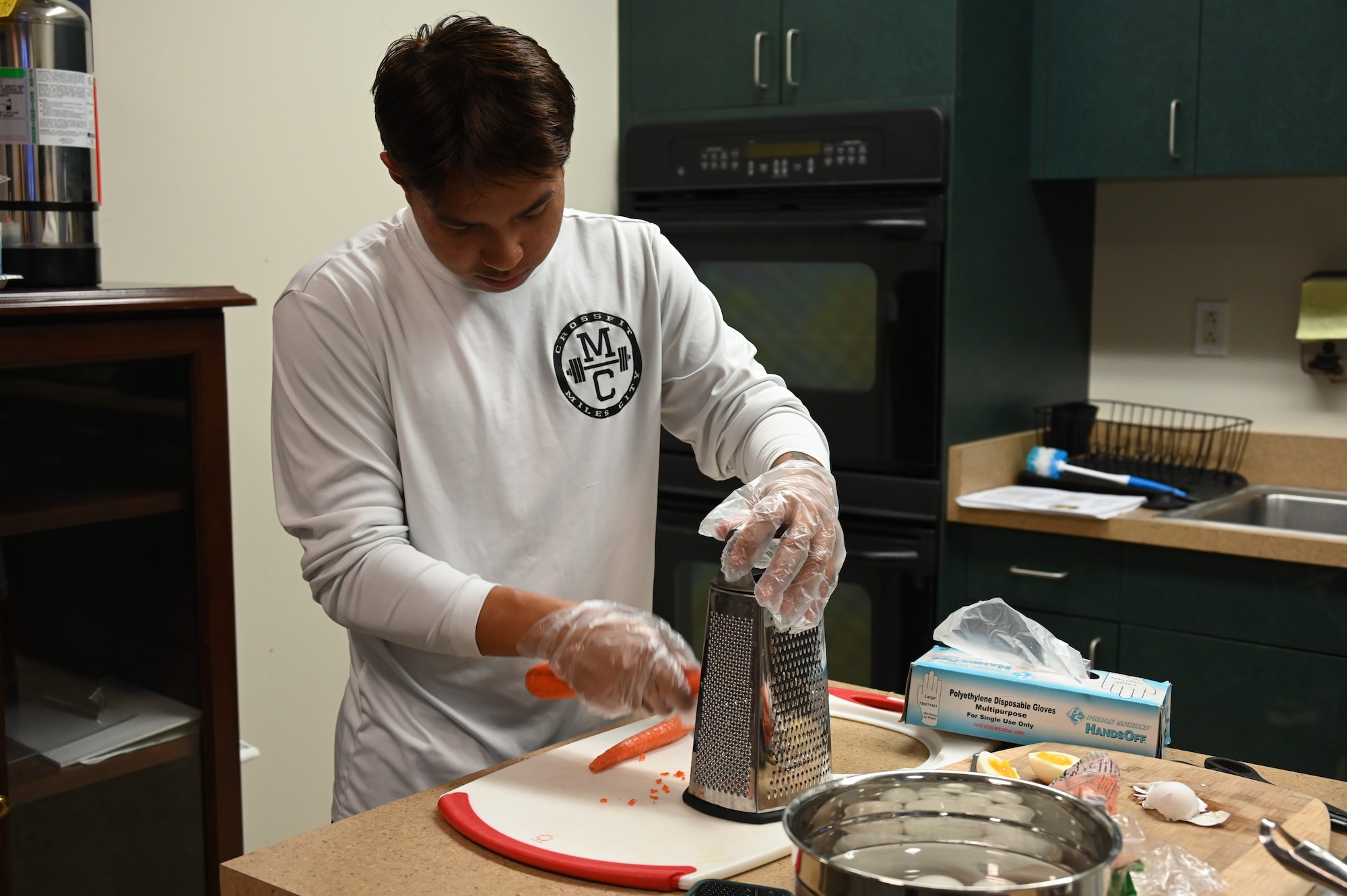 A participant in the Cooking Connections cooking class grates carrots for a ramen recipe at Laughlin Air Force Base, Texas, July 23, 2026. Through hands-on instruction, participants explored techniques for preparing nutritious, affordable meals using everyday ingredients. (U.S. Air Force photo by Airman 1st Class Kylie Rabb)