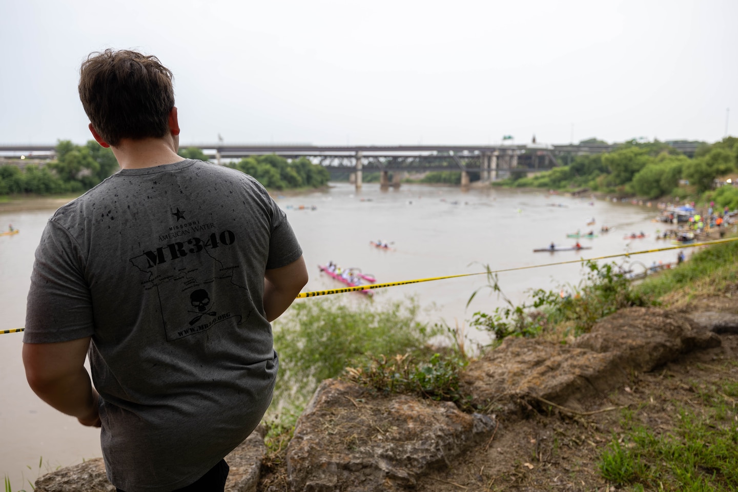 Man watching racers from river bank.