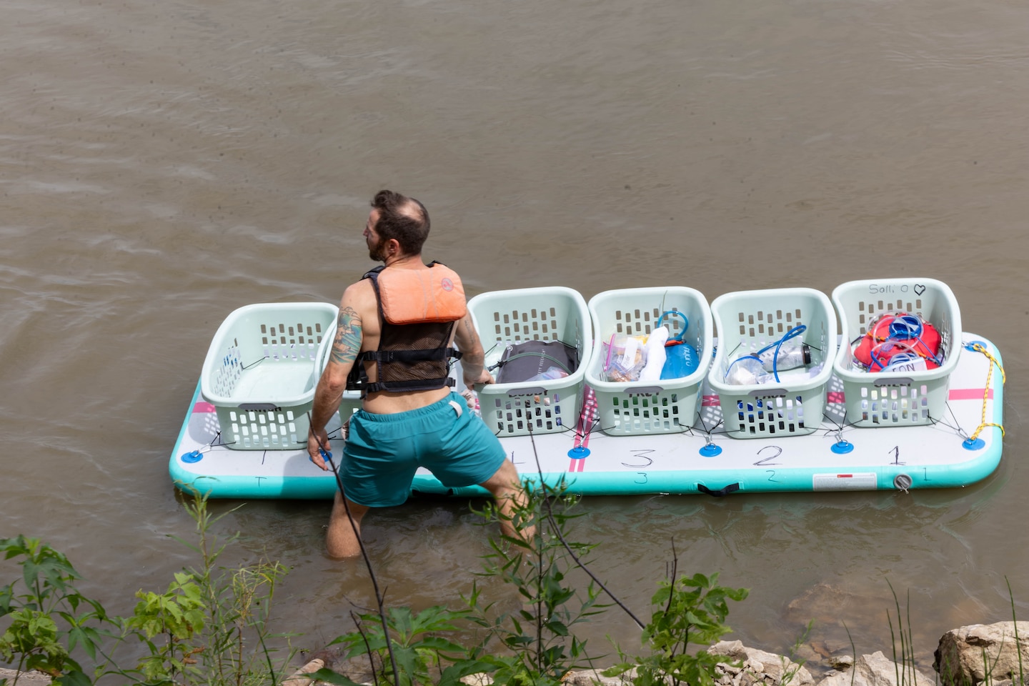 Man standing in river with supplies.