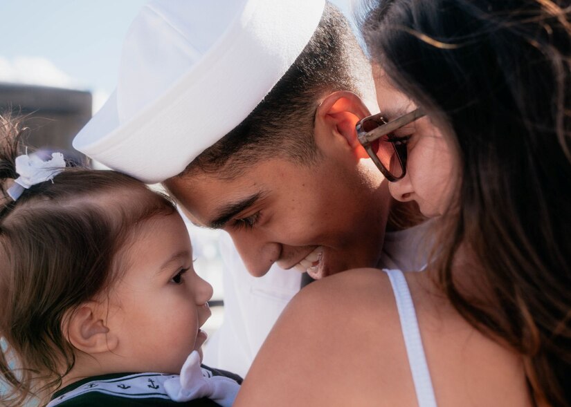 Sailor smiles and hugs wife and toddler