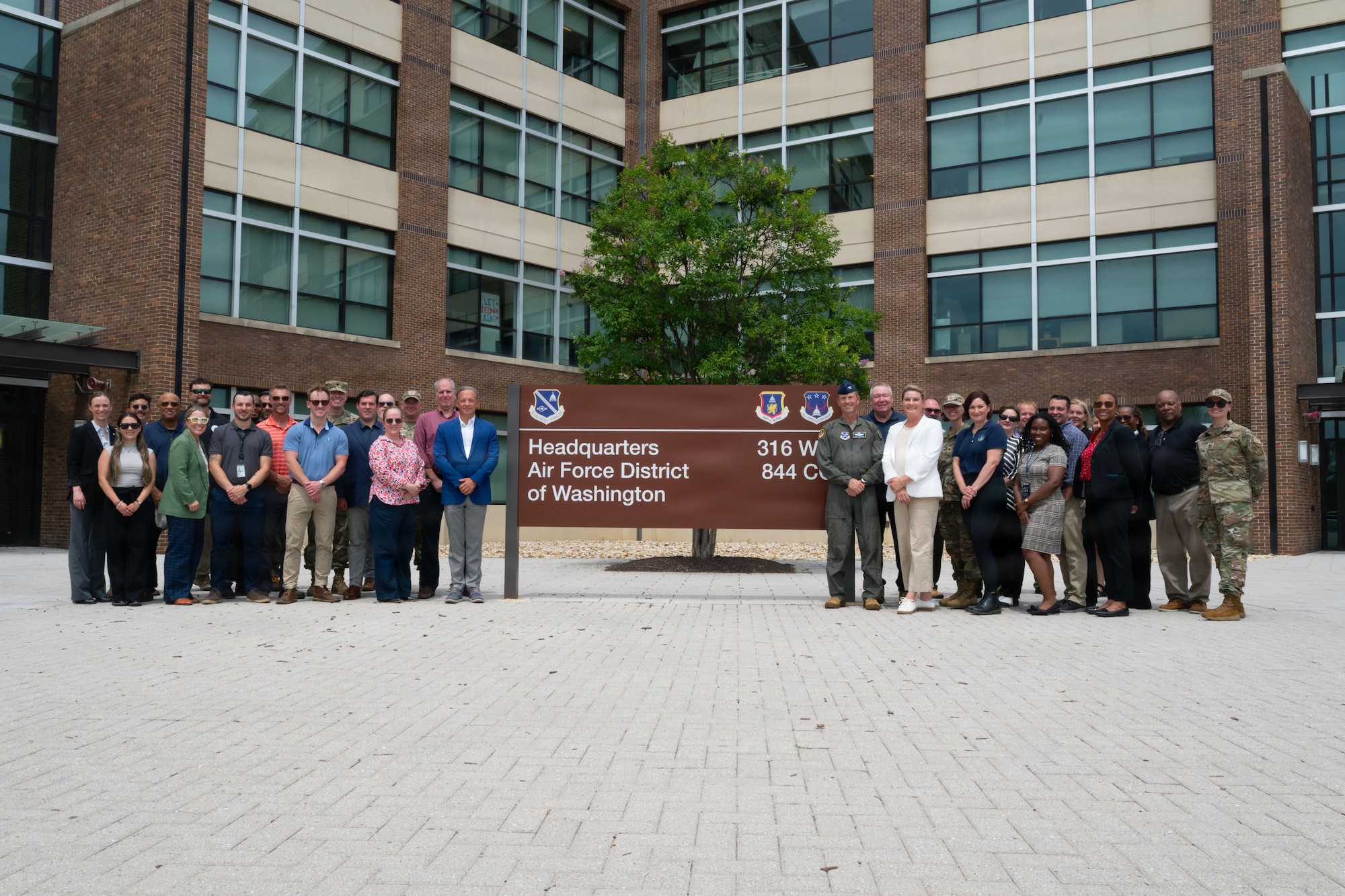 A group of adults stand in front of sign for a picture.