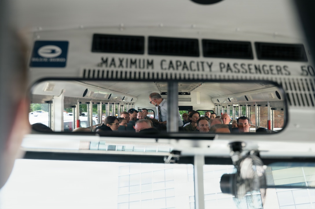 Inside a rearview mirror we see a group of people sitting on a bus.