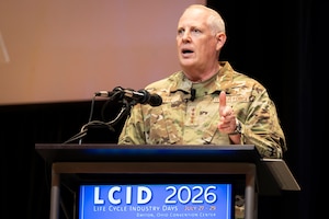 Man in USAF camo stands behind podium and gives speech.