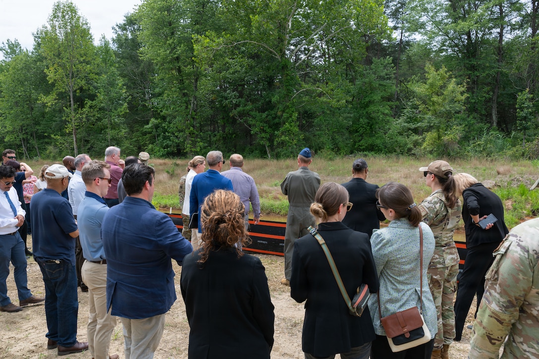 A group of people stand outside and look at a creek.