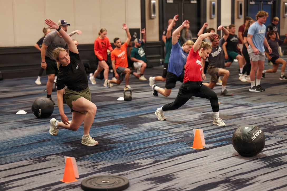 U.S. Marine Corps 2nd Lt. Bailee Mumaw, a student awaiting The Basic School, left, conducts warm up stretches with attendees of the 2026 National Wrestling Coaches Association CEO Leadership Academy during the Fit to Win: Morning Workout in Baltimore, July 29, 2026. Marine Corps Recruiting Command seeks to connect with coaches through the national partnership program, so they return to their schools and communities better equipped to tell the Marine Corps story, ultimately becoming cornerstone advocates. (U.S. Marine Corps photo by Cpl. Brenna Ritchie)