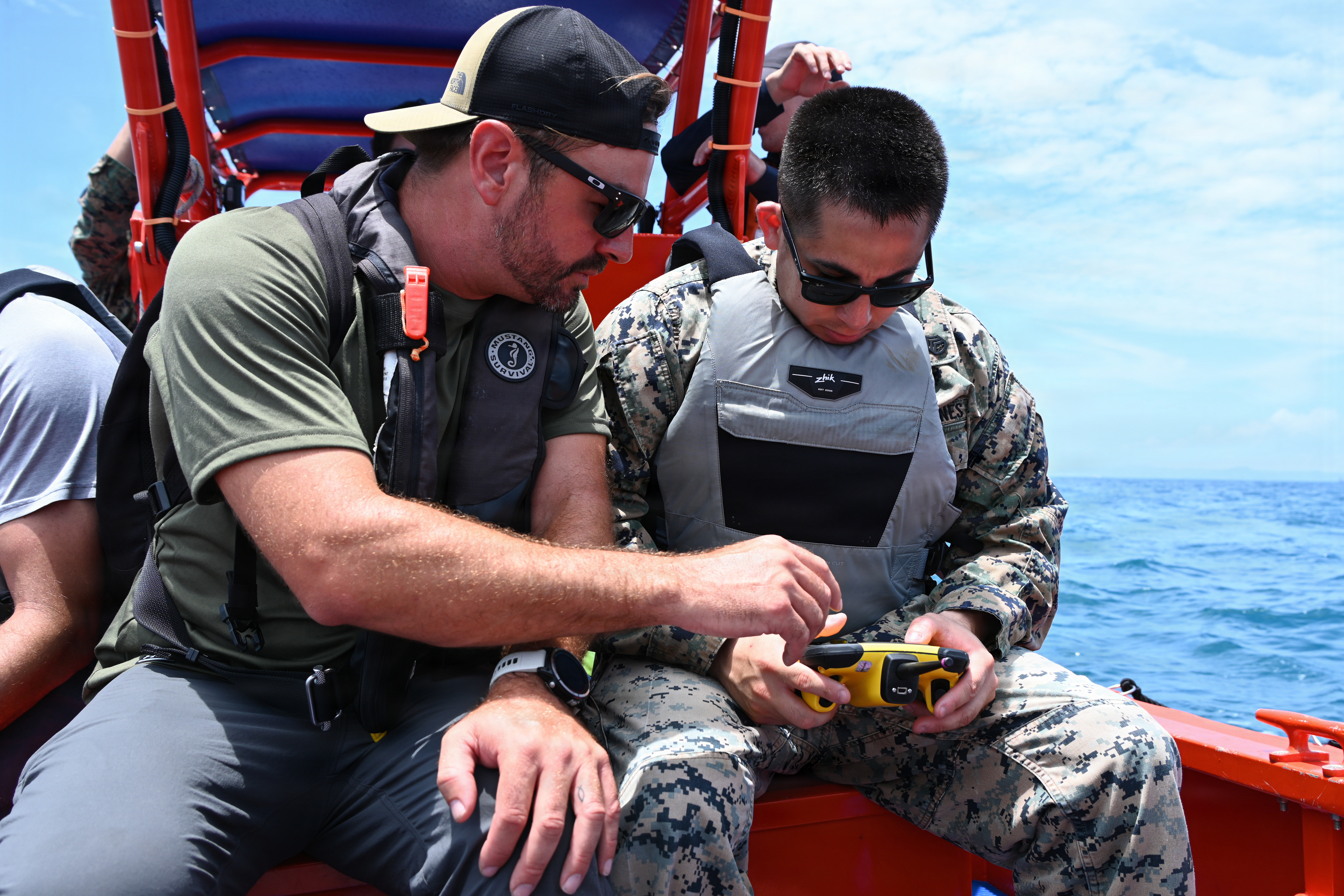 Ryan Faber, left, a Department of Navy civilian with Naval Surface Warfare Center Carderock, shows U.S. Marine Corps Staff Sgt. Joseph Banuelos, a ground electronics systems maintenance technician with Intermediate Repair Company, 3rd Maintenance Battalion, 3rd Marine Logistics Group, how to operate a Fort Robotics remote control to navigate an unmanned Foam Raiding Craft during Valiant Shield 26 at White Beach, Okinawa, Japan, June 29, 2026. The foam craft was created in part by Marines with IRC as part of Resilient Advanced Manufacturing for Contested Environments, or RAMFORCE, an initiative hosted by the Office of the Under Secretary of Defense for Research and Engineering. The innovative event brought together military personnel, government laboratories, and private industry to evaluate how advanced manufacturing technologies could enable expeditionary forces to repair, replace and even produce critical equipment at the point of need. (U.S. Marine Corps photo by Cpl. Rachel Mason)