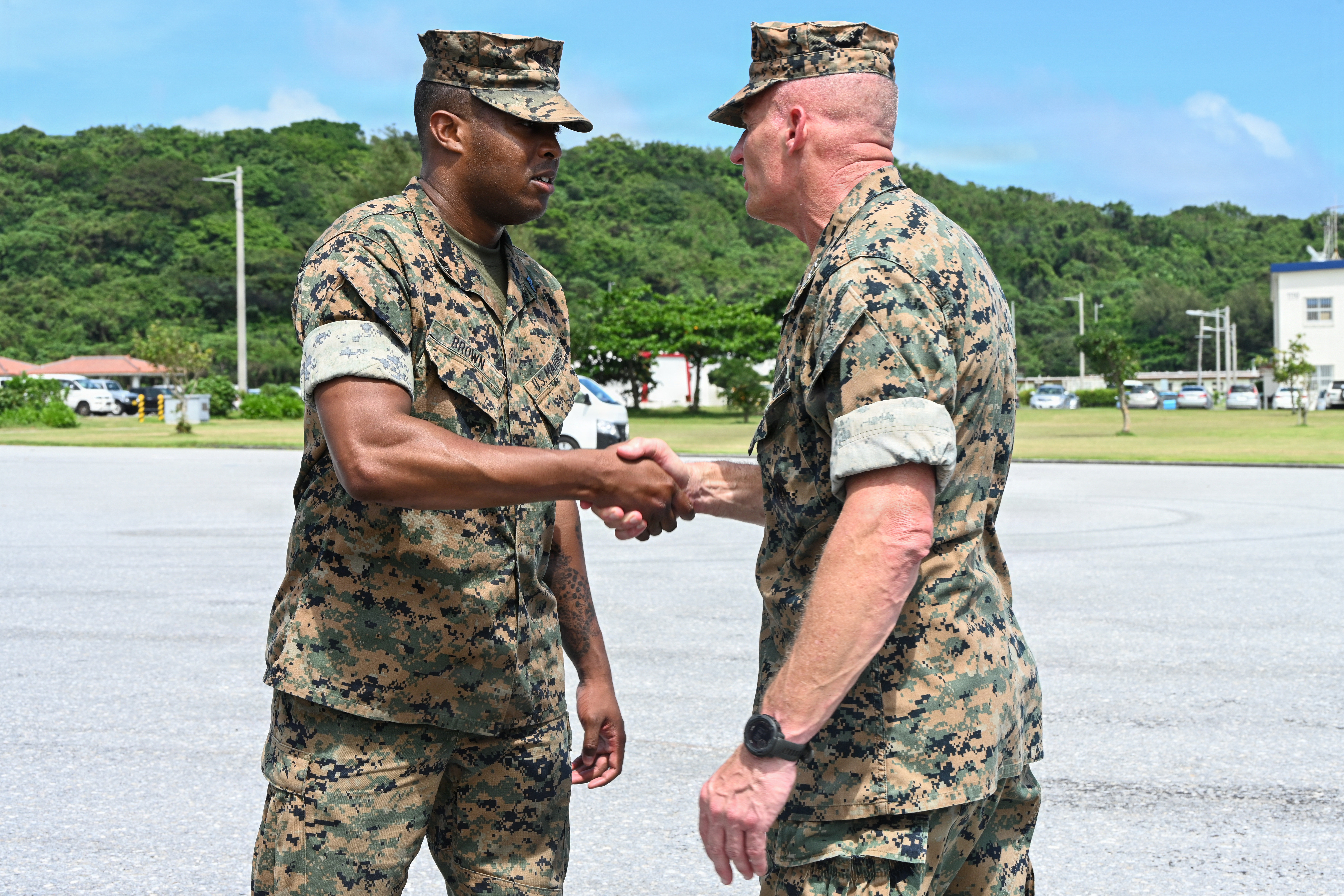 U.S. Marine Corps Sgt. Jamaare Brown, left, a machinist with 9th Engineer Support Battalion, Combat Logistics Regiment 37, 3rd Marine Logistics Group, receives a coin from Lt. Gen. Roger Turner, Commanding General of III Marine Expeditionary Force, during Valiant Shield 26 at White Beach, Okinawa, Japan, June 29, 2026. Intermediate Repair Company participated in Resilient Advanced Manufacturing for Contested Environments, or RAMFORCE, an initiative hosted by the Office of the Under Secretary of Defense for Research and Engineering. The innovative event brought together military personnel, government laboratories and private industry to evaluate how advanced manufacturing technologies could enable expeditionary forces to repair, replace and even produce critical equipment at the point of need. (U.S. Marine Corps photo by Cpl. Rachel Mason)
