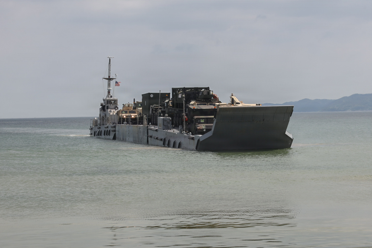 U.S. service members aboard an Improved Navy Lighterage System prepare to conduct a cargo offload during Combined Joint Logistics Over-the-Shore 26 at Dogu Beach, Pohang, South Korea, July 9, 2026. The offload was a Maritime Prepositioning Force exercise where 3rd Marine Logistics Group distributes equipment from a created port of entry and provides support to III Marine Expeditionary Force units training throughout South Korea, testing and validating 3rd MLG’s ability to conduct integrated logistics operations in complex environments. CJLOTS 26 is a combined exercise designed to integrate U.S. and Republic of Korea lighterage and ship-to-shore connector capabilities, improve combined readiness, strengthen the Republic of Korea-U.S. alliance, and expand combined maritime sustainment capacity during logistics operations. (U.S. Marine Corps photo by Lance Cpl. Matthew Borruso)