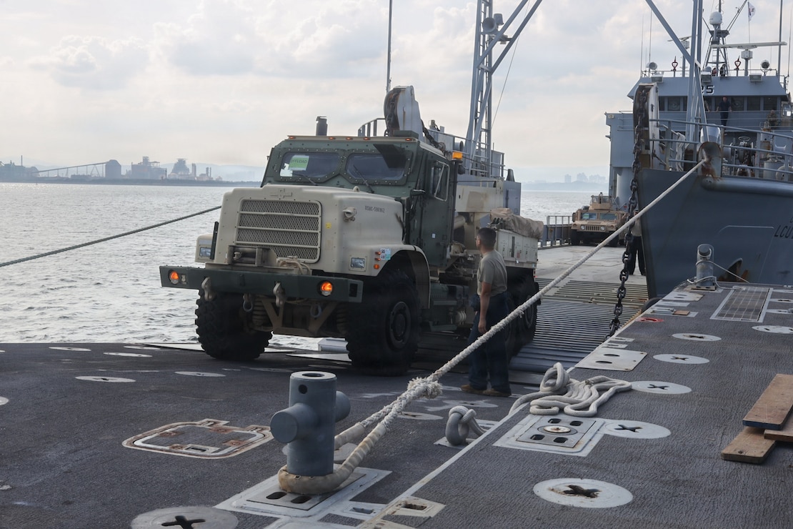 U.S. service members transfer a MK36 Medium Tactical Replacement Vehicle Wrecker onto an Improved Navy Lighterage System to conduct a cargo offload during Combined Joint Logistics Over-the-Shore 26 at Dogu Beach, Pohang, South Korea, July 9, 2026. The offload was a Maritime Prepositioning Force exercise where 3rd Marine Logistics Group distributes equipment from a created port of entry and provides support to III Marine Expeditionary Force units training throughout South Korea, testing and validating 3rd MLG’s ability to conduct integrated logistics operations in complex environments. CJLOTS 26 is a combined exercise designed to integrate U.S. and Republic of Korea lighterage and ship-to-shore connector capabilities, improve combined readiness, strengthen the Republic of Korea-U.S. alliance, and expand combined maritime sustainment capacity during logistics operations. (U.S. Marine Corps photo by Lance Cpl. Matthew Borruso)