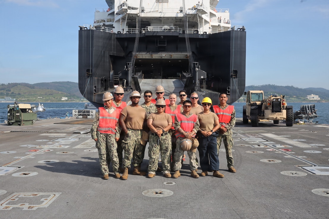 U.S. service members pose for a group photo following a cargo offload for Combined Joint Logistics Over-the-Shore 26 at Dogu Beach, Pohang, South Korea, July 9, 2026. The offload was a Maritime Prepositioning Force exercise where 3rd Marine Logistics Group distributes equipment from a created port of entry and provides support to III Marine Expeditionary Force units training throughout South Korea, testing and validating 3rd MLG’s ability to conduct integrated logistics operations in complex environments. CJLOTS 26 is a combined exercise designed to integrate U.S. and Republic of Korea lighterage and ship-to-shore connector capabilities, improve combined readiness, strengthen the Republic of Korea-U.S. alliance, and expand combined maritime sustainment capacity during logistics operations. (U.S. Marine Corps photo by Lance Cpl. Matthew Borruso)