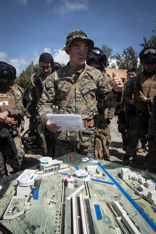 U.S. Marine Corps Capt. Christophe Bittel, a legal assistant officer with Service company, Headquarters battalion, Marine Corps Base Hawaii, briefs Marines using a terrain model during a field exercise at Marine Corps Training Area Bellows, March 26, 2026. The field exercise reinforced combat readiness through realistic, scenario-based training that strengthened coordination, decision making and small-unit leadership. (U.S. Marine Corps photo by Lance Cpl. Tania Guerrero)