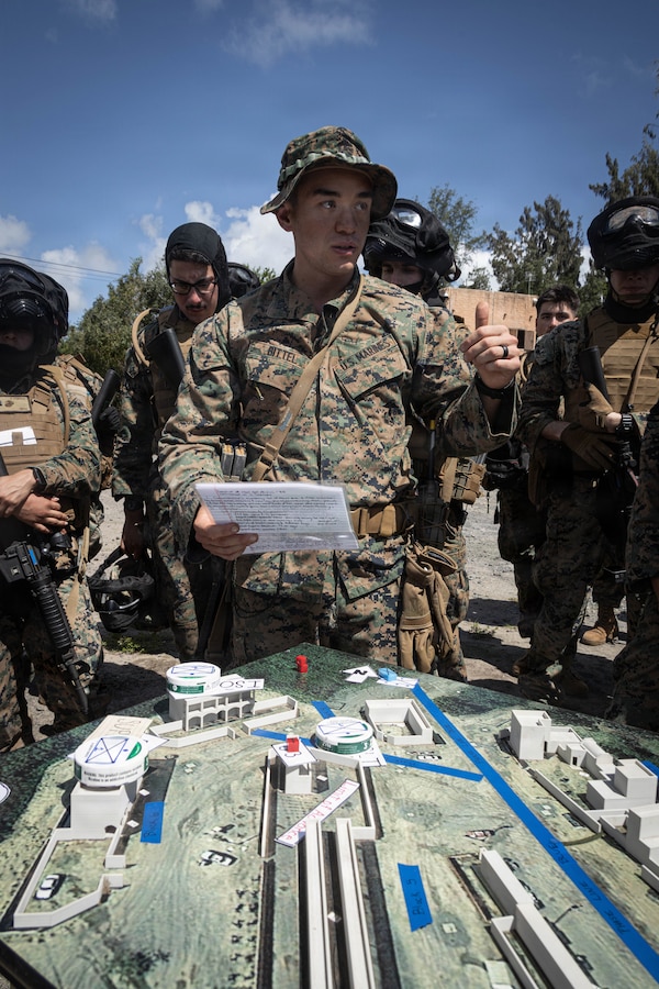 U.S. Marine Corps Capt. Christophe Bittel, a legal assistant officer with Service company, Headquarters battalion, Marine Corps Base Hawaii, briefs Marines using a terrain model during a field exercise at Marine Corps Training Area Bellows, March 26, 2026. The field exercise reinforced combat readiness through realistic, scenario-based training that strengthened coordination, decision making and small-unit leadership. (U.S. Marine Corps photo by Lance Cpl. Tania Guerrero)
