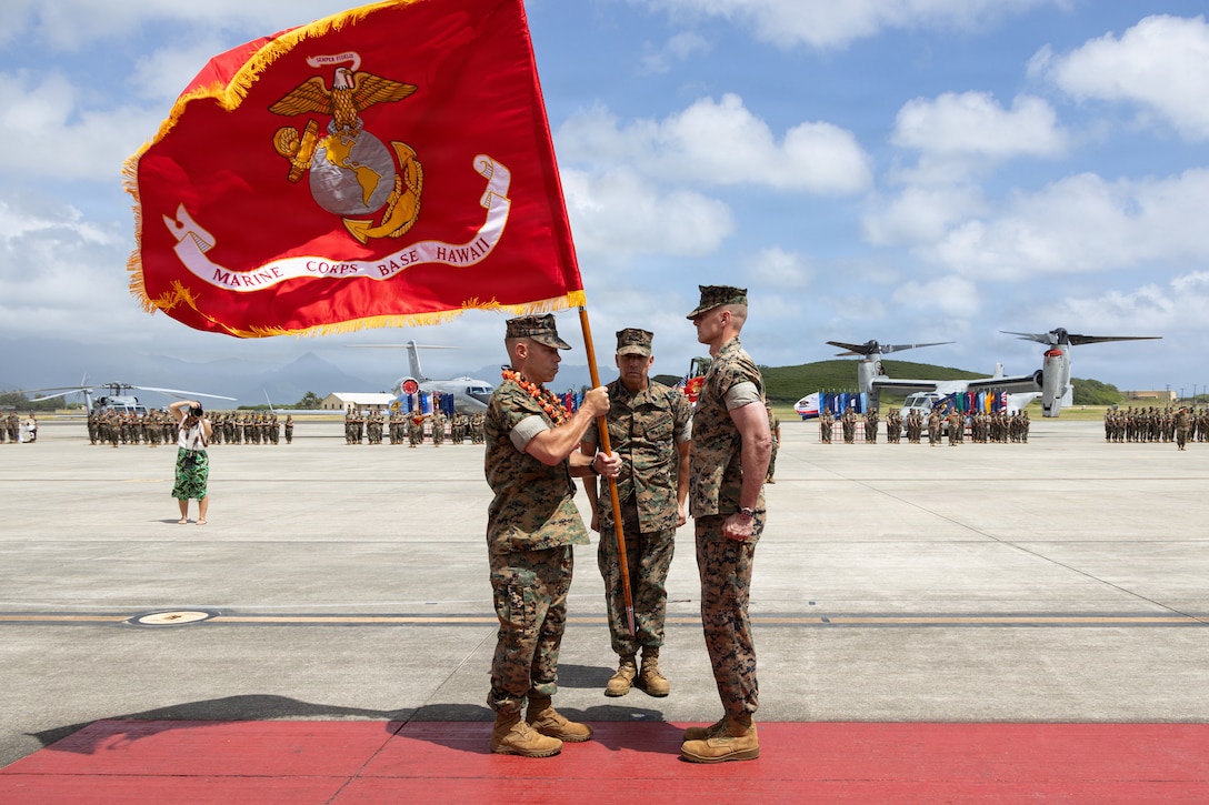 U.S. Marine Corps Col. Stephen DeTrinis, oncoming commanding officer of Marine Corps Base Hawaii, receives organizational colors from Col. Jeremy Beaven, offgoing commanding officer of MCBH, during the MCBH Change of Command Ceremony, May 21, 2026. Col. Jeremy Beaven relinquished command of MCBH to Col. Stephen DeTrinis. (U.S. Marine Corps photo by Lance Cpl. Tania Guerrero)
