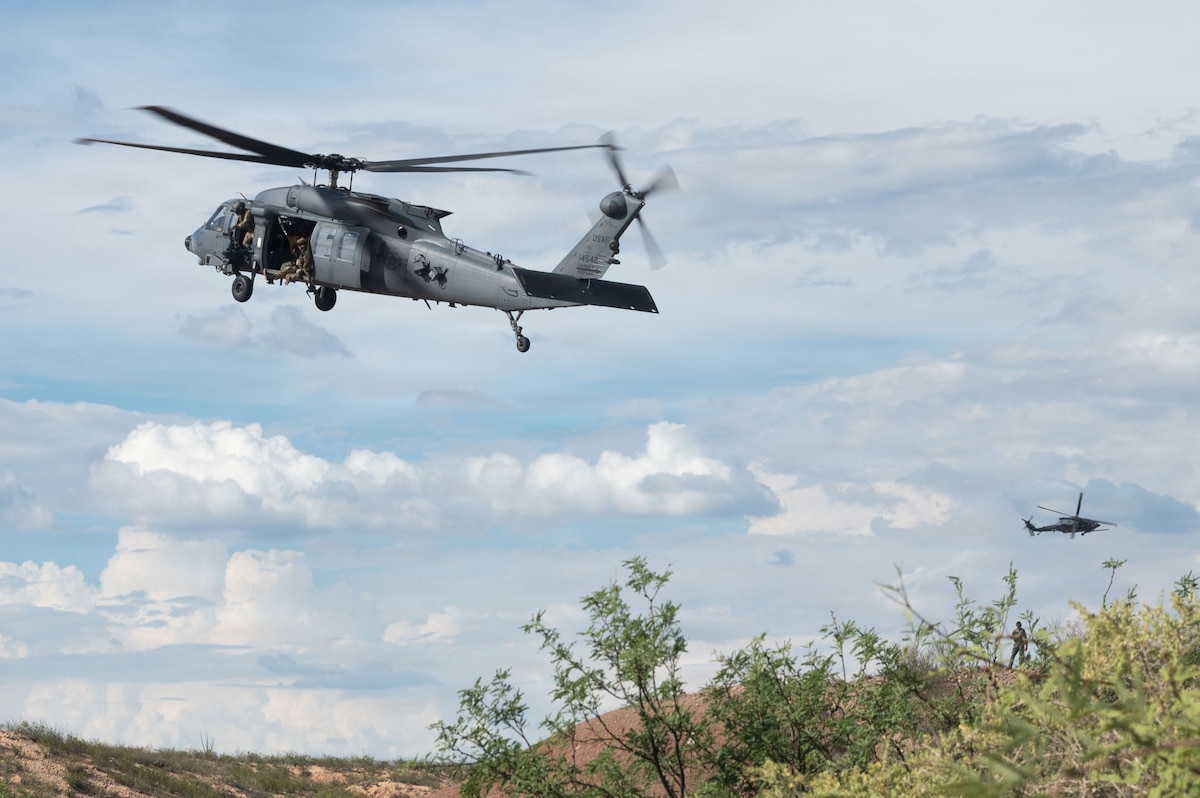 Two HH-60W Jolly Green II aircraft assigned to Davis-Monthan Air Force Base hover over a simulated hostile situation as part of Operation Iron Covenant, a training exercise near Benson, Arizona, July 22, 2026. The aircraft flew sorties in the region in order to determine a proper landing location to begin combat search and rescue operations. (U.S. Air Force photo by Airman Najzee Kuzu)