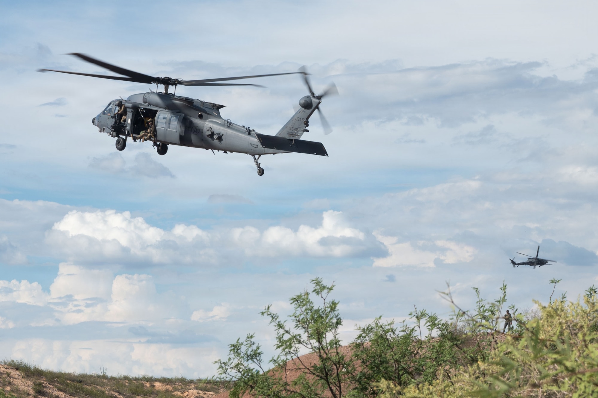 Two HH-60W Jolly Green II aircraft assigned to Davis-Monthan Air Force Base hover over a simulated hostile situation as part of Operation Iron Covenant, a training exercise near Benson, Arizona, July 22, 2026. The aircraft flew sorties in the region in order to determine a proper landing location to begin combat search and rescue operations. (U.S. Air Force photo by Airman Najzee Kuzu)