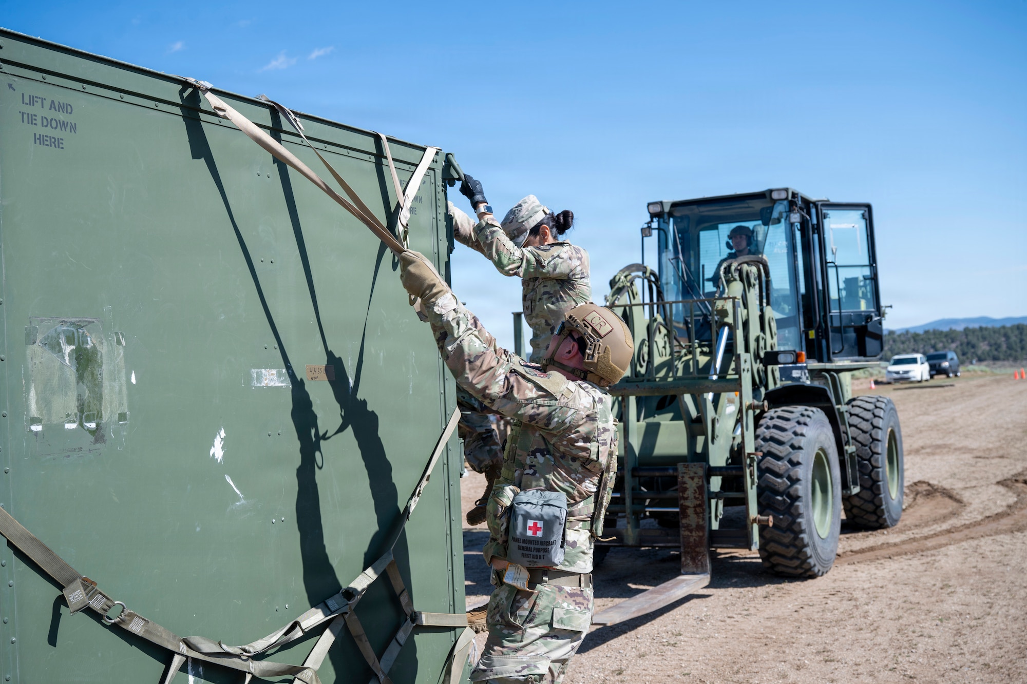 Airmen holds straps around a container.
