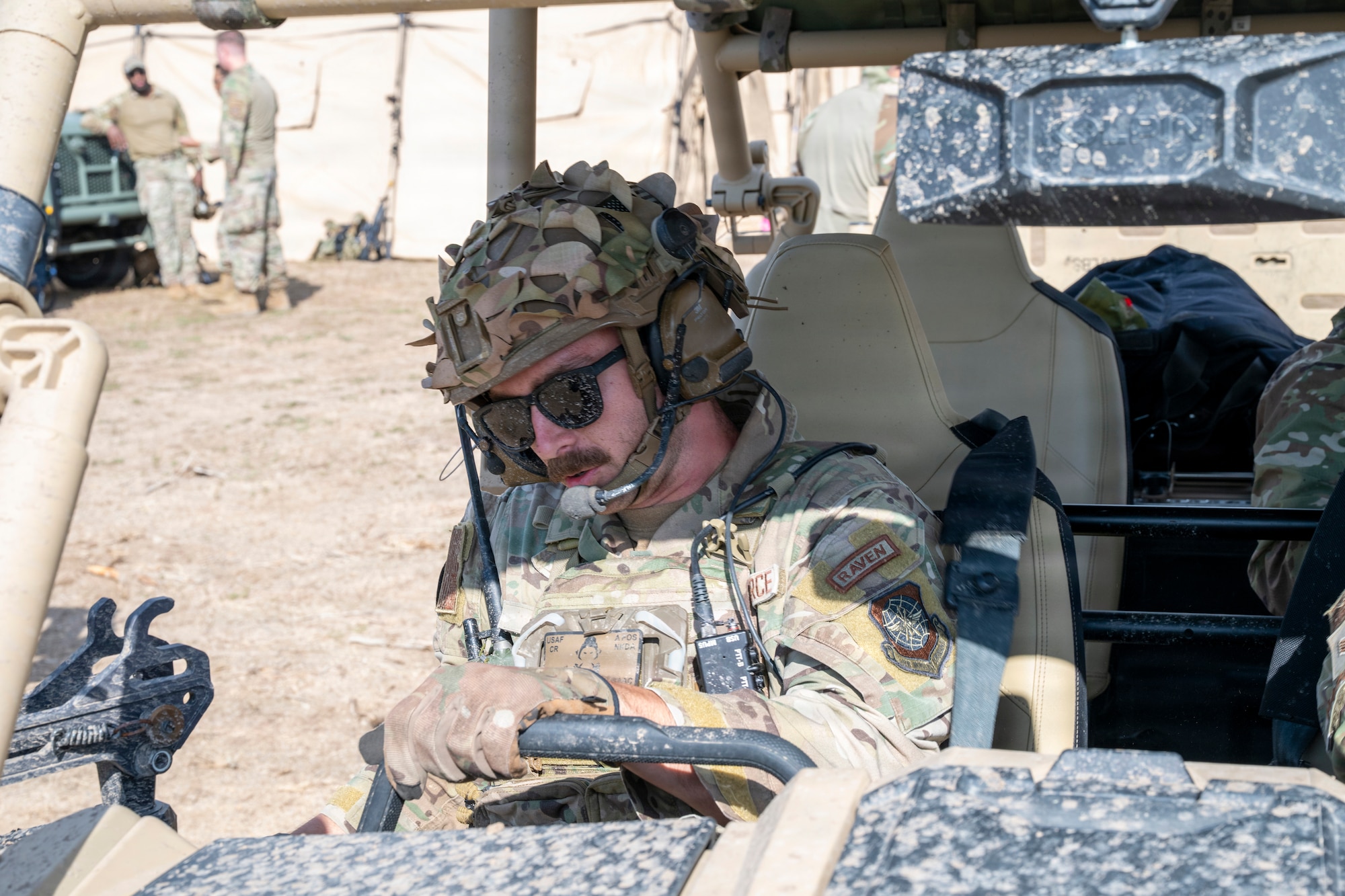 An Airman sits inside a military vehicle.