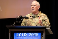 Man in USAF camo stands behind podium and gives speech.