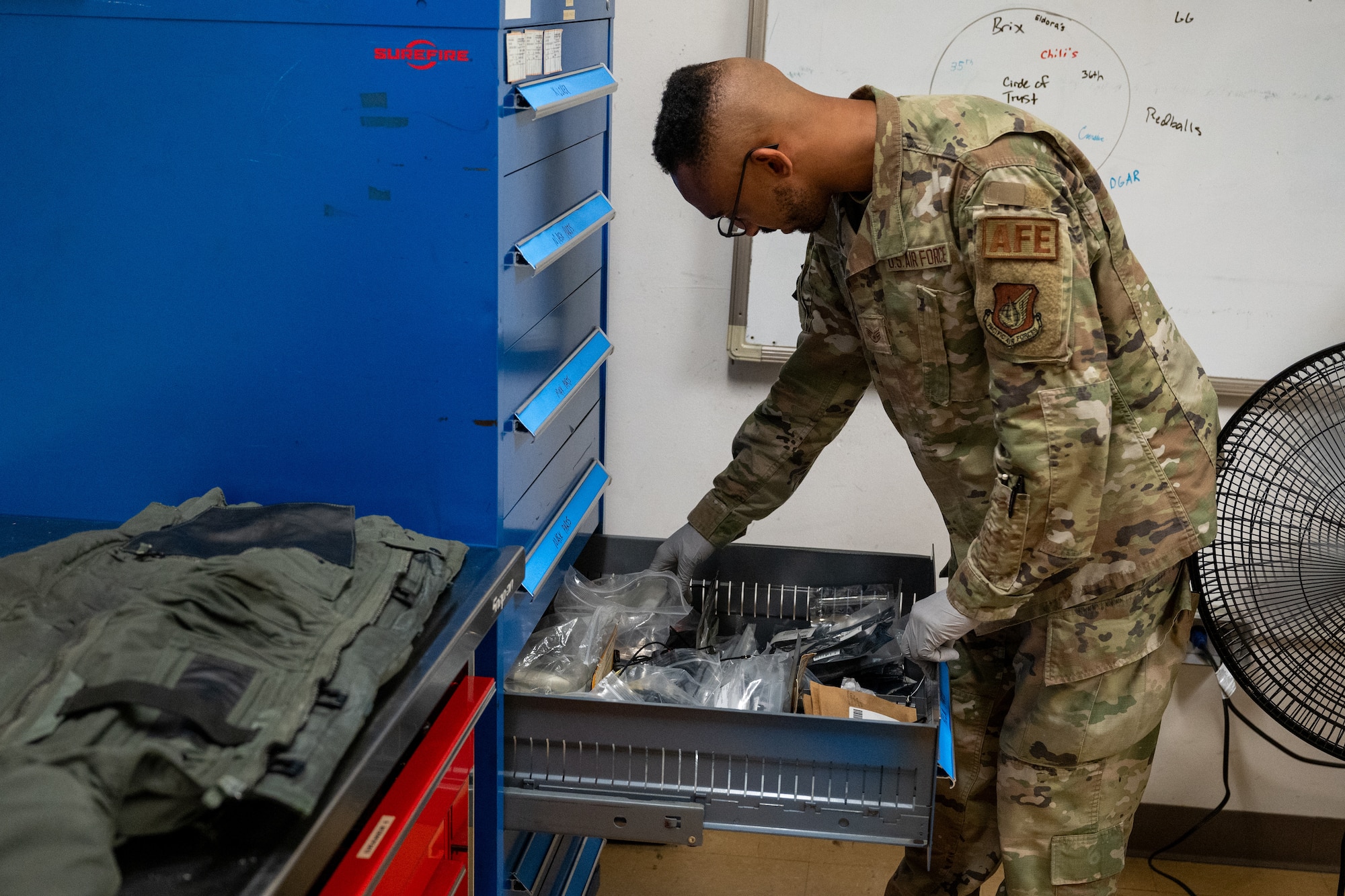 An Airman looks through a drawer for equipment.