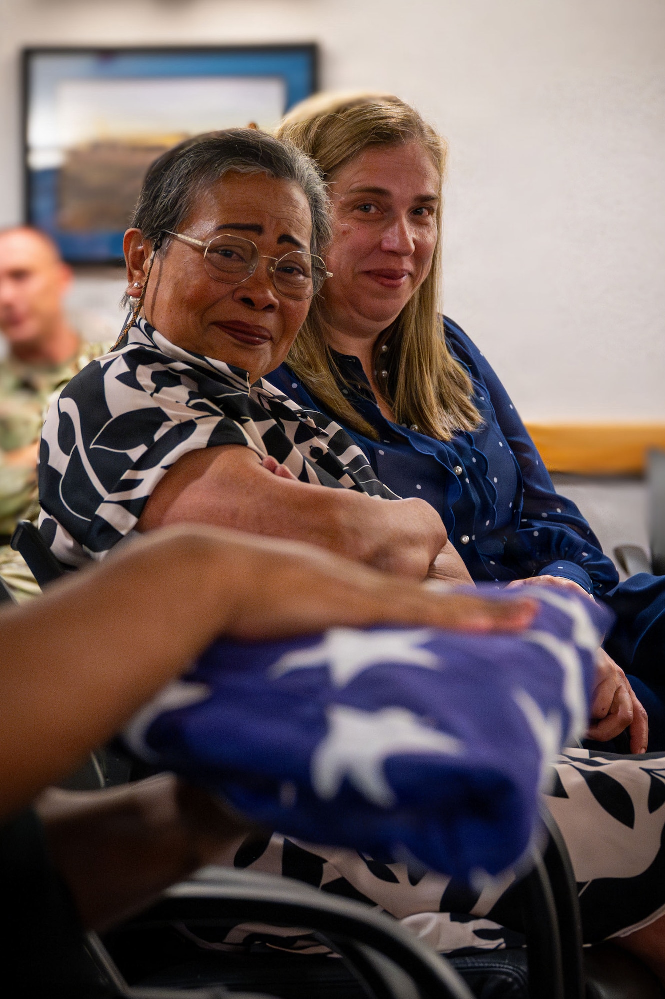 Carla Cherry, right, spouse of U.S. Air Force Master Sgt. Jonathan Cherry, and his mother, Anita Washington, watch the passing of the flag during Cherry’s retirement ceremony at RAF Mildenhall, England, July 9, 2026.