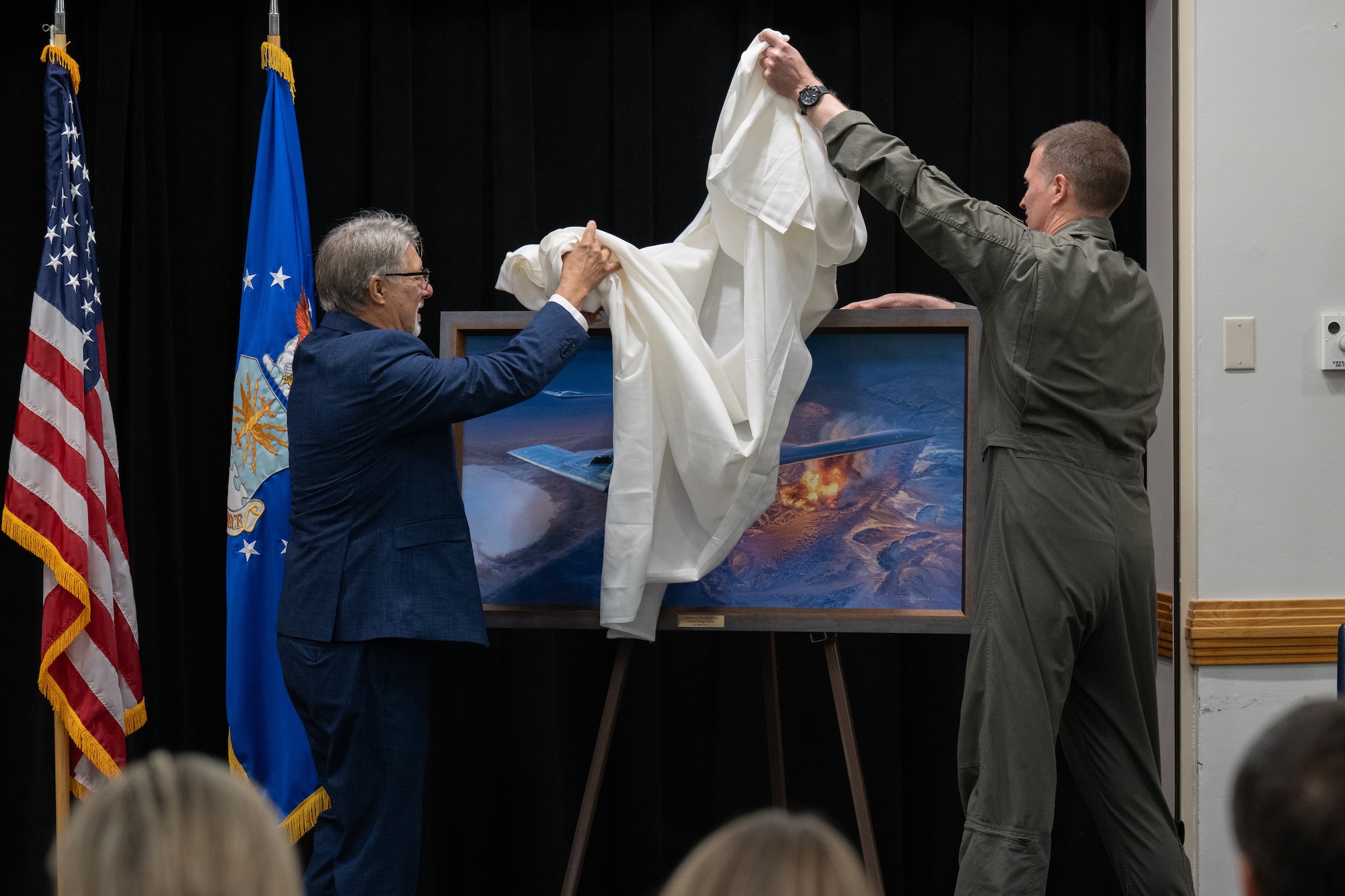 U.S. Air Force Col. Joshua Wiitala, 509th Bomb Wing commander, right, and Rick Herter, artist of “Slamming the Door Shut,” unveil the painting at Whiteman Air Force Base, Missouri, July 28, 2026. The painting depicted B-2 Spirit aircraft during Operation Midnight Hammer and was presented to the 509th Bomb Wing for successfully executing the mission. (U.S. Air Force photo by Senior Airman Matthew S. Domingos)