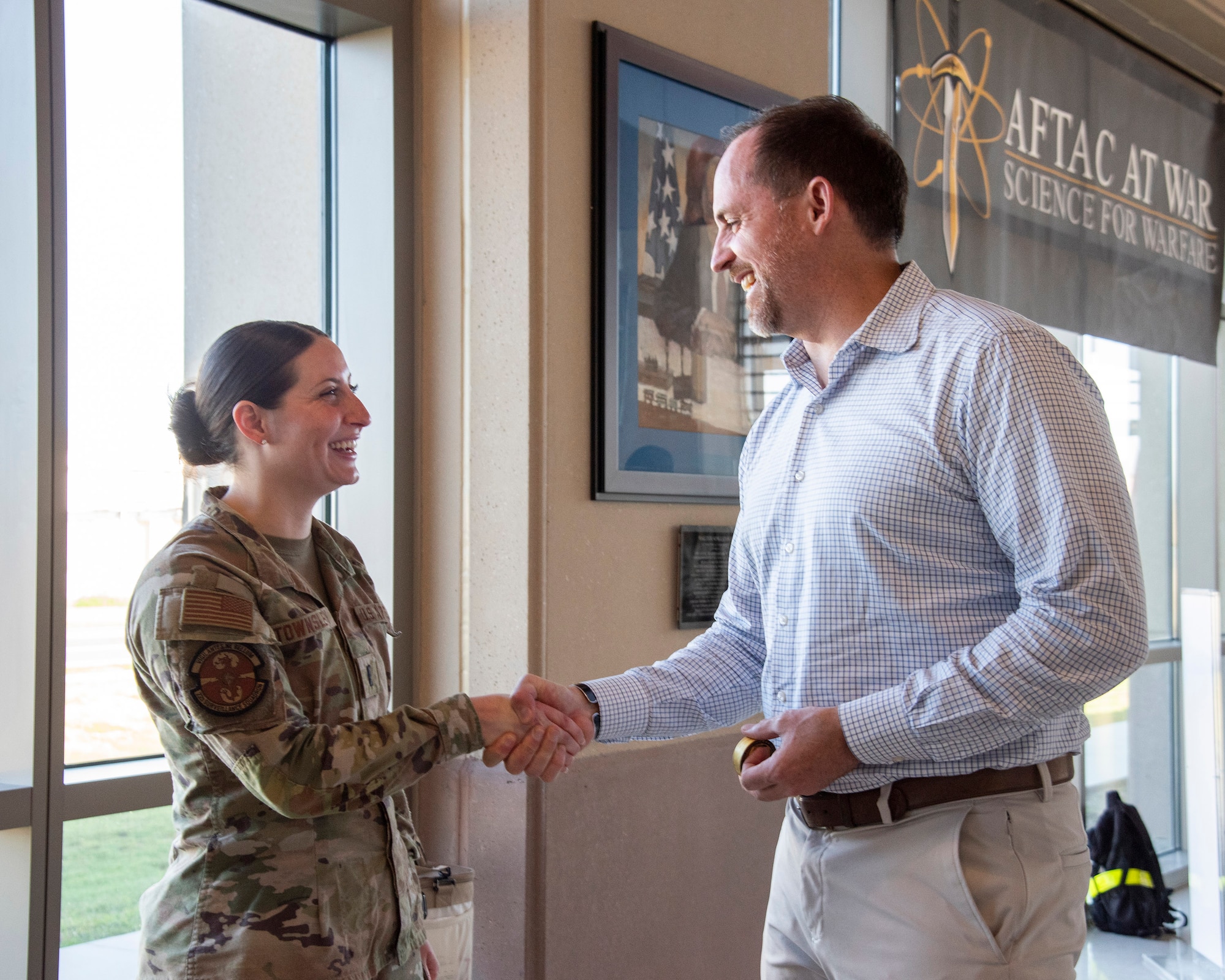 Under Secretary of War (I&S) Bradley Hansell presents his coin to 1st Lt. Gabrielle Townsley for her role in standing up the Air Force Technical Applications Center's Rapid Response Mission Planning Cell during Operation Epic Fury.  (Air Force photo by Susan A. Romano)