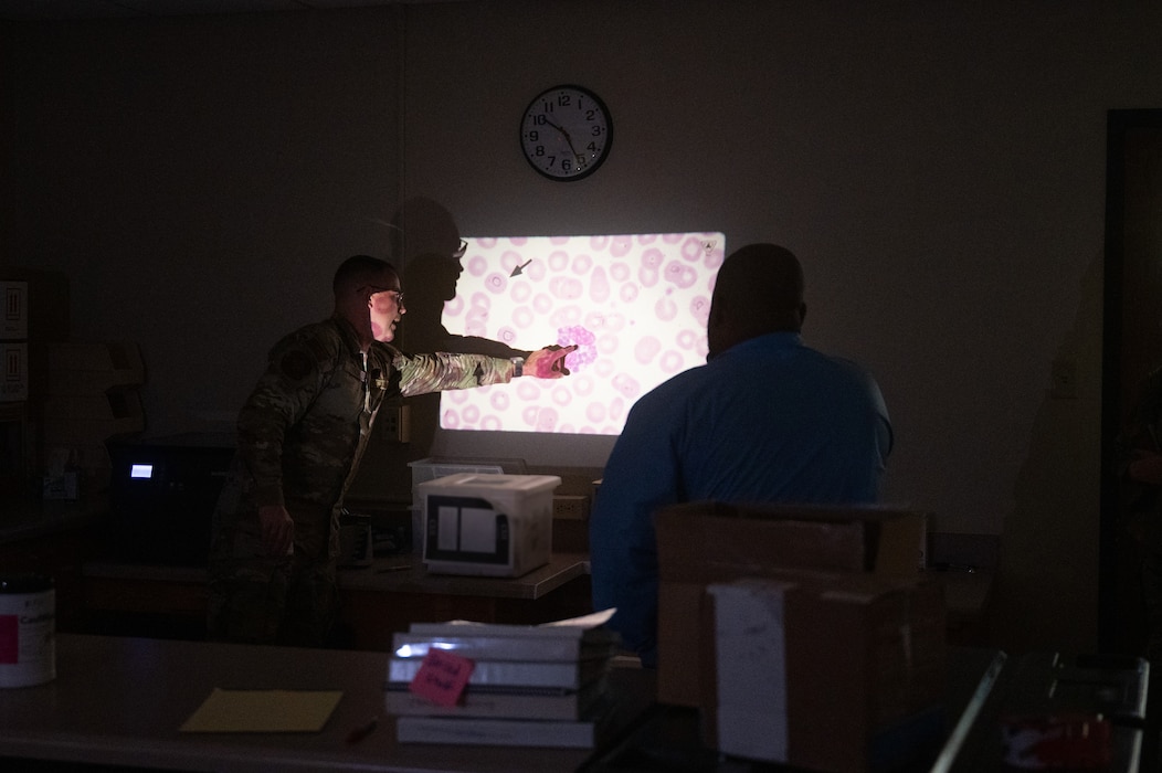 U.S. Air Force 1st Lt. Christopher Bedics, Goodfellow Medical Group laboratory element chief, and Staff Sgt. Justin Turner, GMDG laboratory noncommissioned officer in charge, showcase the different cells found in blood during the Distinguished Educators’ Tour inside the Ross Clinic laboratory, Goodfellow Air Force Base, Texas, July 21, 2026. Laboratory technicians need a high attention to detail to quantify and classify cells and their abnormalities. (U.S. Air Force photo by Senior Airman Brian Lummus) Portions of this image were blurred for OPSEC purposes.
