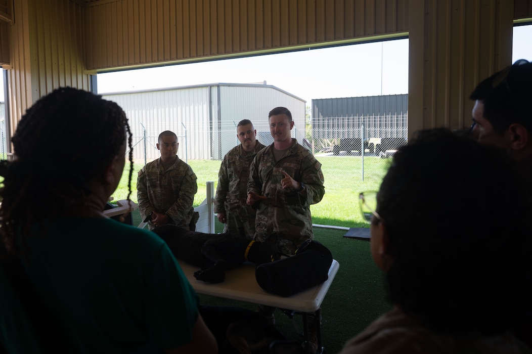U.S. Air Force Tech. Sgt. Alan Muhle, 17th Security Forces military working dog handler, briefs educators on the capabilities of the K-9s utilized by the U.S. Air Force during the Distinguished Educators’ Tour at the MWD kennels, Goodfellow Air Force Base, Texas, July 21, 2026. MWDs are used in patrols, drug and explosive detection and specialized mission functions for the Department of War. (U.S. Air Force photo by Senior Airman Brian Lummus)