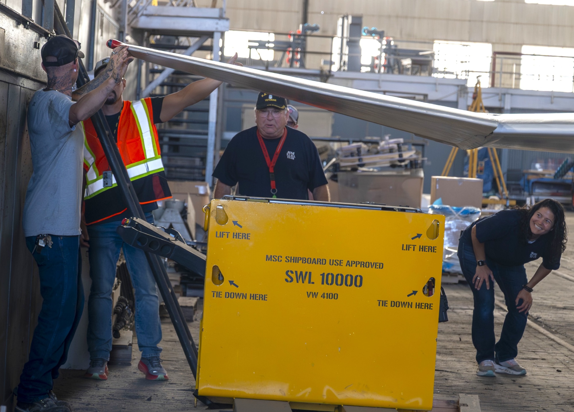 Volunteers ensure there is safe clearance between the wing tip of a newly restored F-4 Phantom II military aircraft and storage containers in Hangar 1 at Joint Base McGuire-Dix-Lakehurst, N.J., July 1, 2026. The aircraft, which took a team of volunteers 13 months to restore, was being transported from Hangar One to its new location as a static display in Navy Lakehurst Air Park at JB MDL. (U.S. Air Force photo by Susan Moriarty)