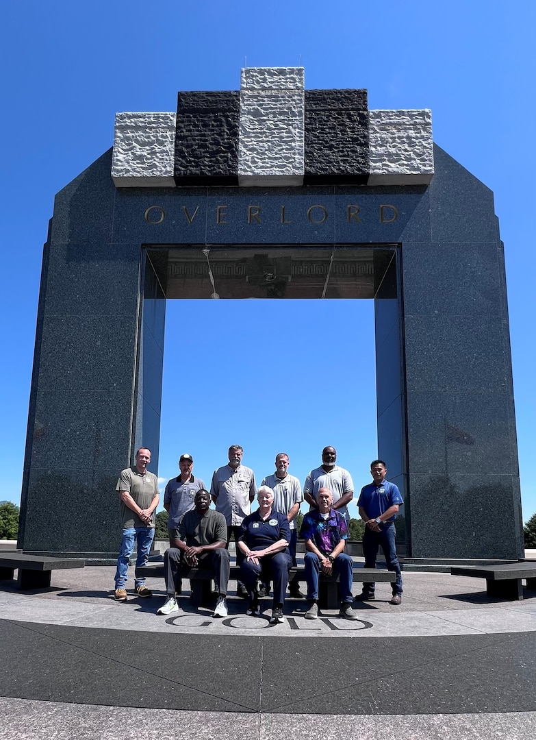 A group poses for a photo in front of a war memorial