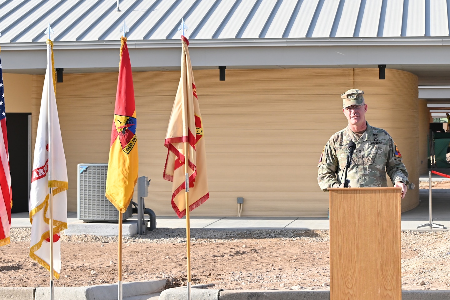 Maj. Gen. Curtis Taylor, Commanding General of the 1st Armored Division and Fort Bliss, addresses those in attendance during a ribbon-cutting ceremony at Fort Bliss marking the completion of the first of 10 3D-printed buildings to be completed for the new Joint Task Force, Southern Border Campus.
“Together, they offer over 78,000 square feet of covered area that houses up to 560 service members,” said Maj. Gen. Curtis Taylor, Commanding General of the 1st Armored Division. “These facilities were fully 3D-printed in just 58 days and delivered in less than four months. This is the largest deployment of robotic construction capabilities in the history of the Department of War. By leveraging this emerging technology, we built these barracks four times faster than the typical construction model and 9% cheaper than our initial estimates. Saving the American taxpayer over $5.6 million just in overhead. But this project is more than impressive statistics, 3D-printing or cost savings.”