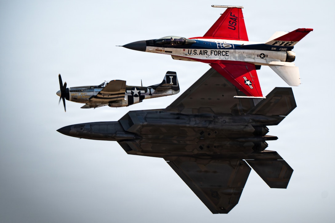 Three red, white and blue aircraft fly in triangular formation toward the left in a gray sky.