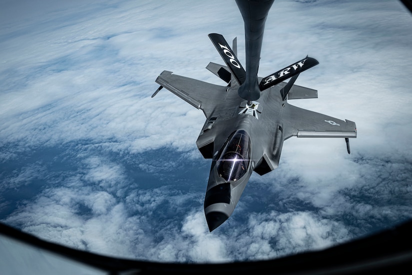 A fighter jet is connected to the boom of a tanker aircraft while refueling in flight.