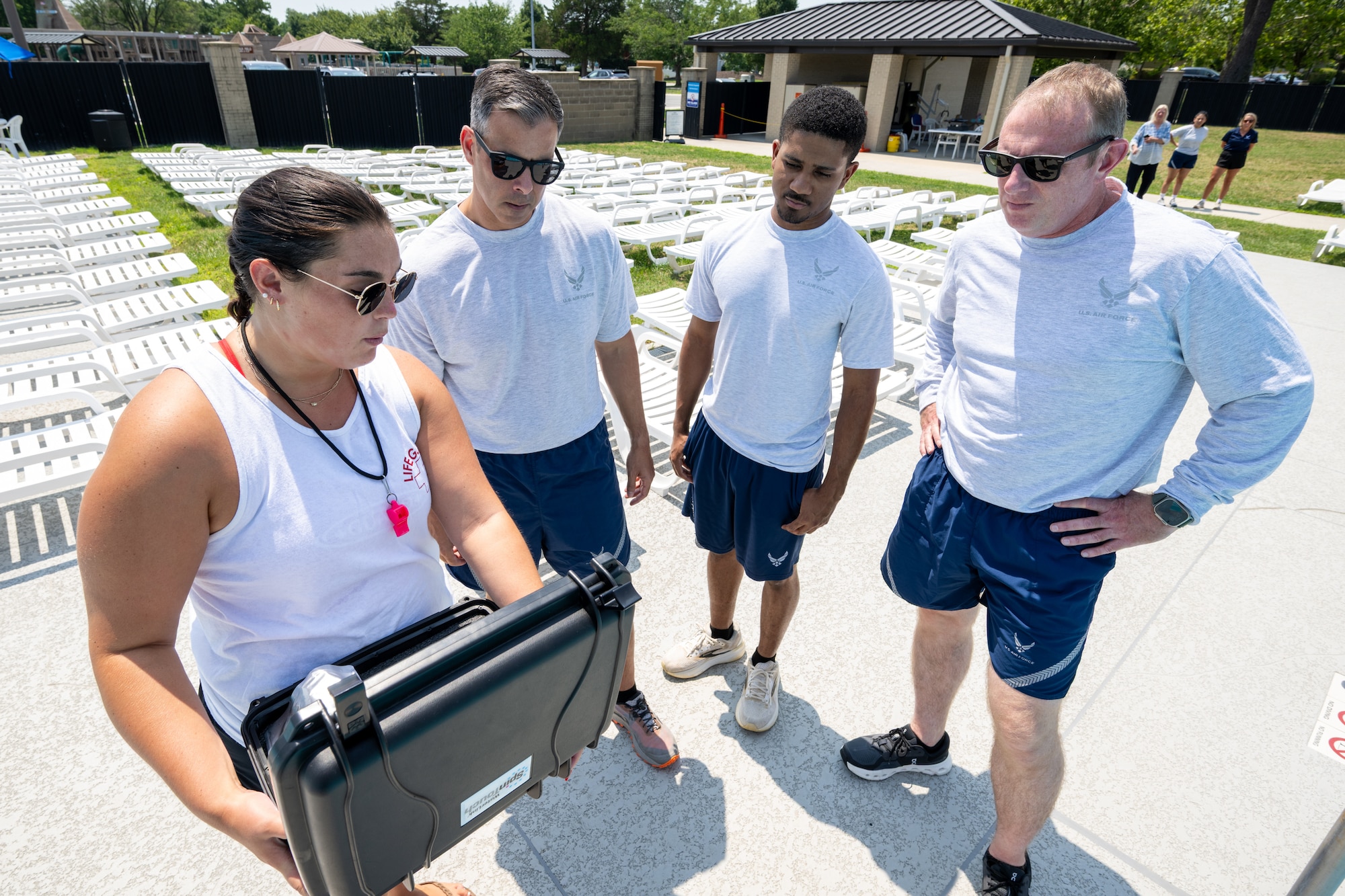 Allison Hemberger, left, 436th Force Support Squadron aquatic supervisor, shows U.S. Air Force Col. Jamil Musa, 436th Airlift Wing commander, Airman 1st Class Malachi Reape, 436th Health Care Operations Squadron medical technician and Chief Master Sgt. Elijah Edwards, 436th AW command chief, her daily tasks during a Dover Duties visit to the Oasis Pool at Dover Air Force Base, Delaware, July 15, 2026. Throughout the visit, the command team and Reape learned about pool operations, lifeguarding responsibilities and the day-to-day efforts required to operate the recreational facility. Reape noted working alongside wing leadership and getting to know them was a highlight of the visit. (U.S. Air Force photo by Mauricio Campino)