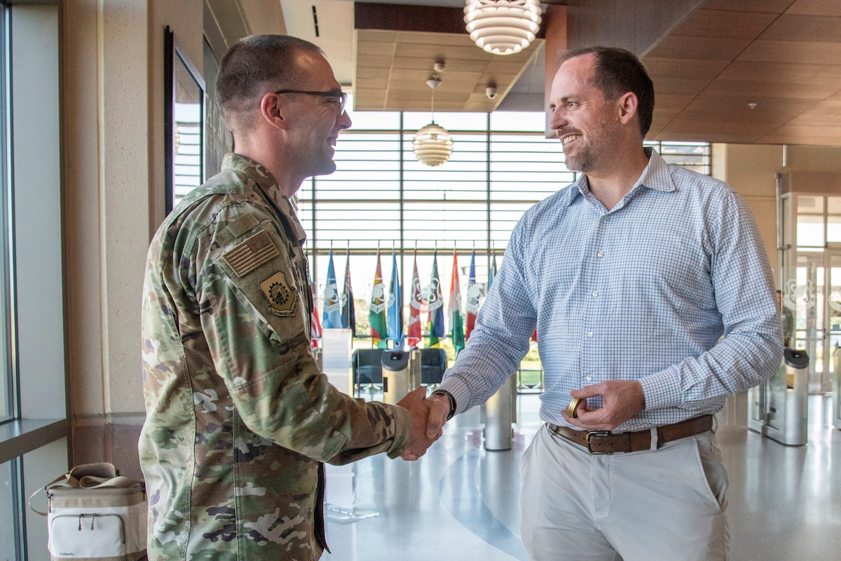Under Secretary of War (I&S) Bradley Hansell congratulates Tech. Sgt. Brian Ebling of the Air Force Technical Applications Center for delivering immediate force protection for 7,800 deployed personnel as lead acoustic developer within the first 48 hours of Operation Epic Fury.  (U.S. Air Force photo by Susan A. Romano)