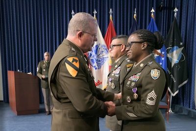 An Army general shakes hands with a female soldier after awarding her a Purple Heart medal.
