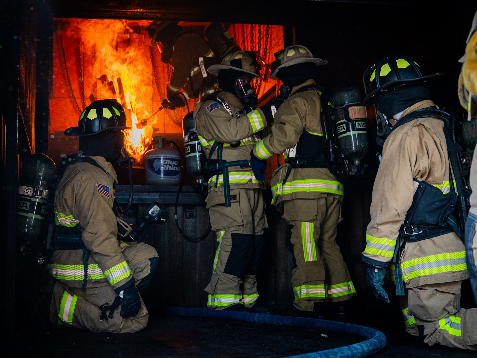 A photo of a group of fire fighters in a room with a fire.