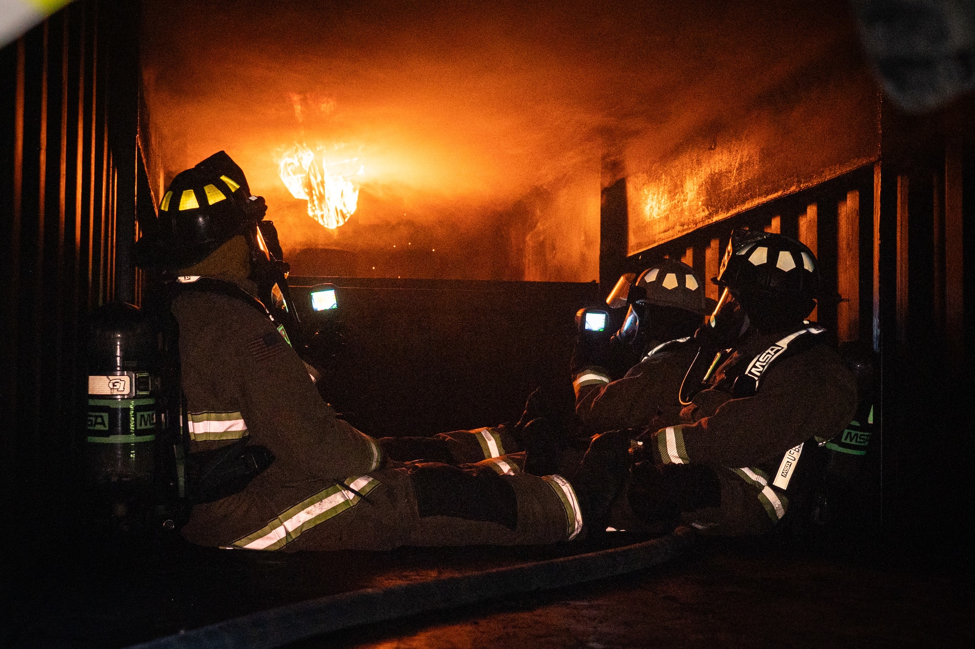 A photo of a group of firefighters sitting in a room.